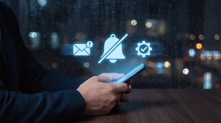 Person silencing smartphone notifications with do not disturb icon at night by a rainy window