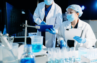 Medical scientists conducting laboratory research using digital tools and lab equipment. Healthcare, biotechnology, diagnostics, and clinical research teamwork concept.