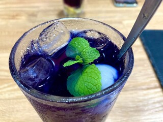 butterfly pea flower iced tea with mint leaf and ice cubes in a glass