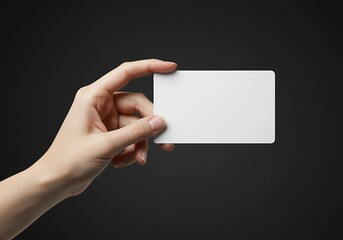 Hand holding a blank white business card against a dark background