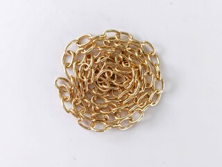 Gold cable chain coiled into circular spiral on white background.