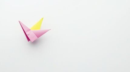 Delicately Folded Pink and Yellow Origami Boat Resting on a Minimalist Light Gray Surface
