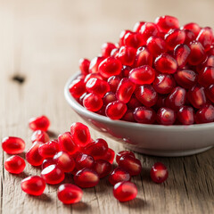 Fresh pomegranate seeds in white bowl on wooden table