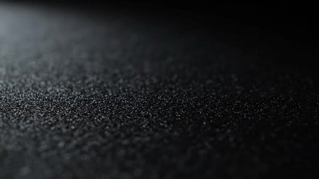 A close-up view reveals a textured, speckled surface fading into darkness, lit from above