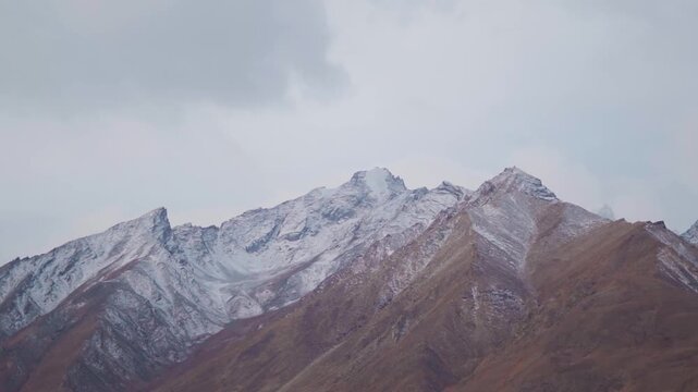Landscape shot of snow covered Himalayan mountain peaks during a cloudy day in winter season as seen from Padum town in Zanskar Valley of Ladakh, India. Scenic view of snowy Himalayas in Padum. 