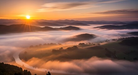 Aerial view of a misty valley and winding river at sunrise, with layered mountain silhouettes in the distance
