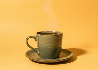 Steaming Hot Coffee in a Green Ceramic Mug on a Yellow Background