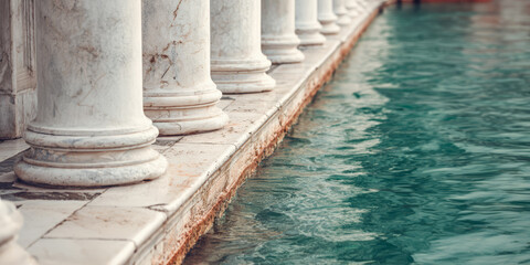 Columns stand near water reflecting light in a calm setting during daytime hours in a serene location