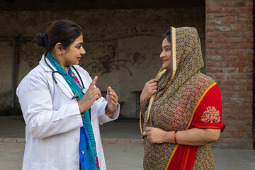 Female doctor consulting rural Indian woman patient. Healthcare professional spread health...