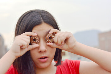 A kid covering the eyes with two round cookies, imitating round surprised eyes.