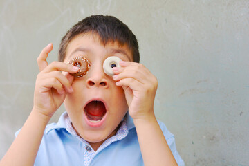 A kid covering the eyes with two round cookies, imitating round surprised eyes.