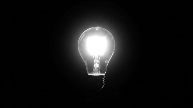 Bright Lit Incandescent Light Bulb On In Dark Room Demonstrating Energy, Electricity and Inspiration