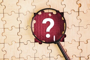 magnifying glass and wooden puzzle with question mark. concept of question or answer. Search or...