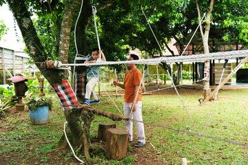 Father guiding his son through outdoor skills training in a natural environment. Emphasizes mentorship, sustainable lifestyle, and experiential learning.