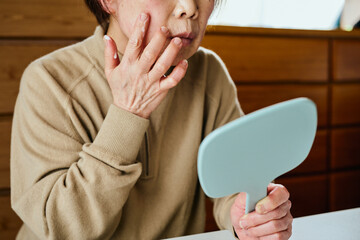 顔に保湿クリームを塗るシニア女性