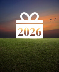 Gift box happy new year 2026 flat icon on green grass field over sunset sky, Business happy new year 2026 shopping concept