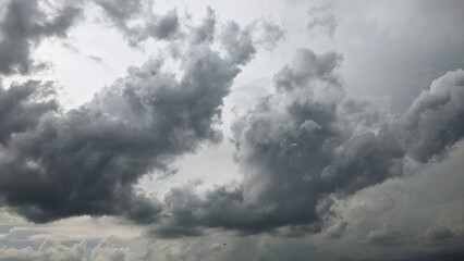 Moody dark grey storm clouds forming in bright overcast sky.