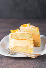 Two pieces of vanilla sponge cake with orange cream and mousse on white plate