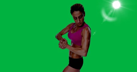 Female bodybuilder flexing her muscles against spot of light on black background