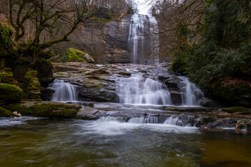 Fototapeta premium A serene view of Suuçtu Waterfall in Bursa, with water cascading over moss-covered rocks, surrounded by lush greenery and trees, creating a peaceful, natural landscape perfect for nature lovers.