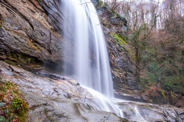 A serene view of Suu&ccedil;tu Waterfall in Bursa, with water cascading over moss-covered rocks, surrounded by lush greenery and trees, creating a peaceful, natural landscape perfect for nature lovers.