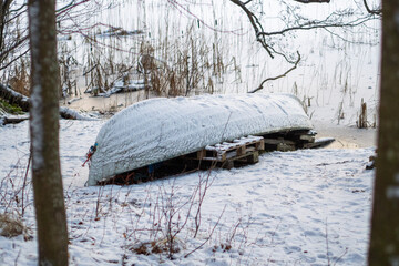 Snow covered canoe on wooden dock in winter landscape