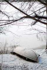 Snowy boat on frozen lake, winter landscape serene