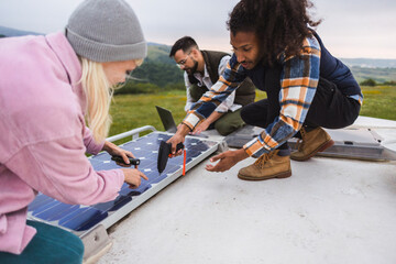 Diverse friends installing solar panels on van roof