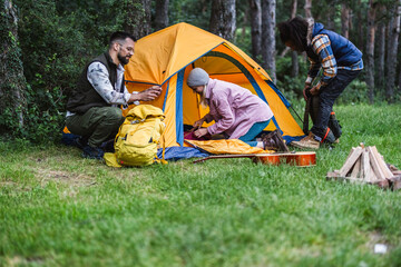 Friends setting up tent during camping trip in forest