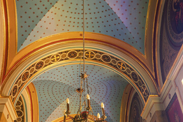 Ceiling detail in the Church of Saint Nicholas in Ermoupolis, Syros, Greece, featuring a light blue dome adorned with red dots arranged in concentric circles and geometric patterns.