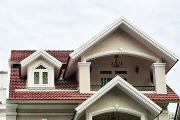 Detailed Architectural Close-up Showcasing The Intricate White Trim And Deep Red Terracotta Roof Tiles Of A Luxurious, Multi-gabled Stucco Residence Against A Bright Sky