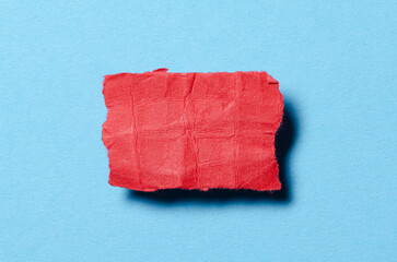 One single red torn ripped wrinkled crumpled blank paper note with shadow and copy space for text on blue background