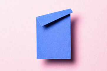 Blue blank paper note cardboard with folded corner dog-ear earmark, shadow and copy space for text on pink background