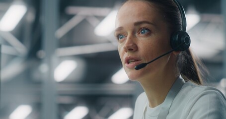 Close Up of Professional Adult Woman Wearing Headset While Communicating With Colleague IT Engineers. Concept of Concentration and Role in Modern, Sophisticated Technical Environment. Portrait.