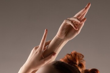 Elegant female hands and arms raised in a graceful, artistic pose against a neutral background