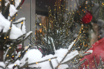 Christmas trees decorated with garlands stand on the street near the cafe.