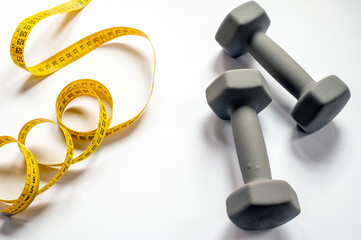 Fitness And Measurement: Yellow Tape Measure And Gray Dumbbells For Home Workout