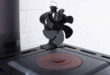 Stove fan heat powered. Black heat stove fan on the top of wood stove to improve heat circulation. Eco-friendly home heating concept