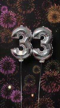 Silver balloon number 33 with fireworks in the background. Festive scene for birthday or anniversary party