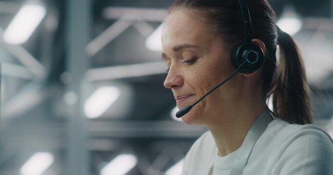 Close Up of Professional Adult Woman Wearing Headset While Communicating With Colleague IT Engineers. Concept of Concentration and Role in Modern, Sophisticated Technical Environment. Portrait.
