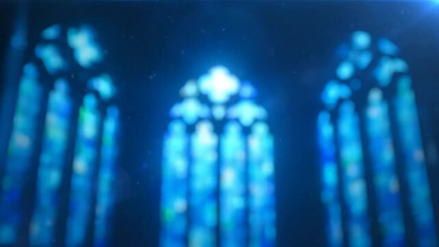 Blurred view of ornate stained glass church windows bathed in blue light and dust motes