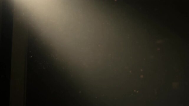 Dramatic Light Beam Shining Down on Dark Background with Dust Particles.