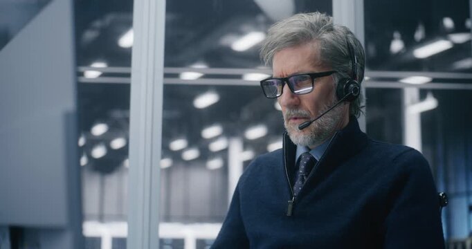 Close Up of Mature Professional in Call Center Setup, Answering Critical Technical Issues With Headset in Large, Modern Server Hall. Concept Twenty Four Seven Support and Operational Readiness. - Powered by Adobe