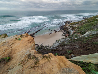 Atlantic Ocean waves crashing on a sandy beach below cliffs