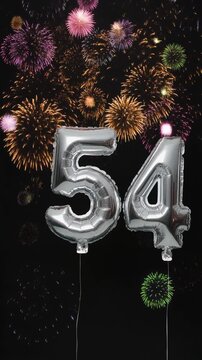 Silver balloon number 54 with fireworks in the background. Festive scene for birthday or anniversary party