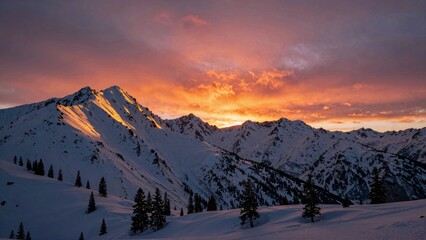 Snowy mountain range at sunset with orange sky and pine trees