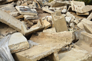 A messy pile of broken concrete slabs and construction debris shows rusty metal reinforcements and...