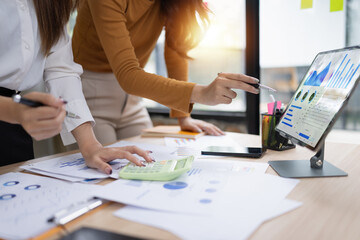 Two asian businesswoman using digital tablet and talking about business with analyzing financial charts in the modern office.