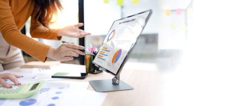 Two asian businesswoman using digital tablet and talking about business with analyzing financial charts in the modern office. - Powered by Adobe