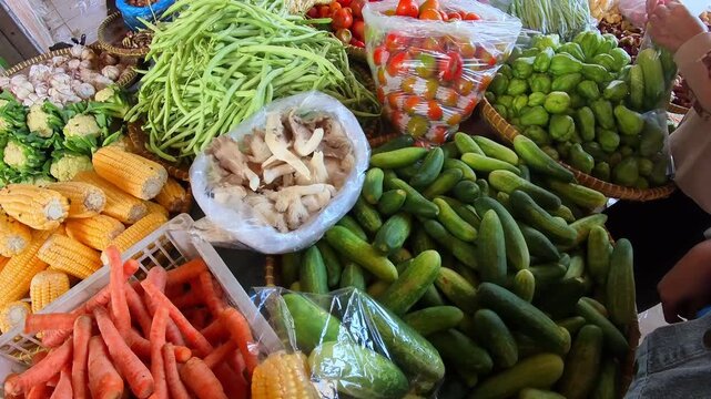 Clip of a variety of vegetables such as cucumbers, carrots, corn, green beans, mushrooms, and cauliflower at a traditional Indonesian market. Videography of vegetables placed on a table in 4K HD.